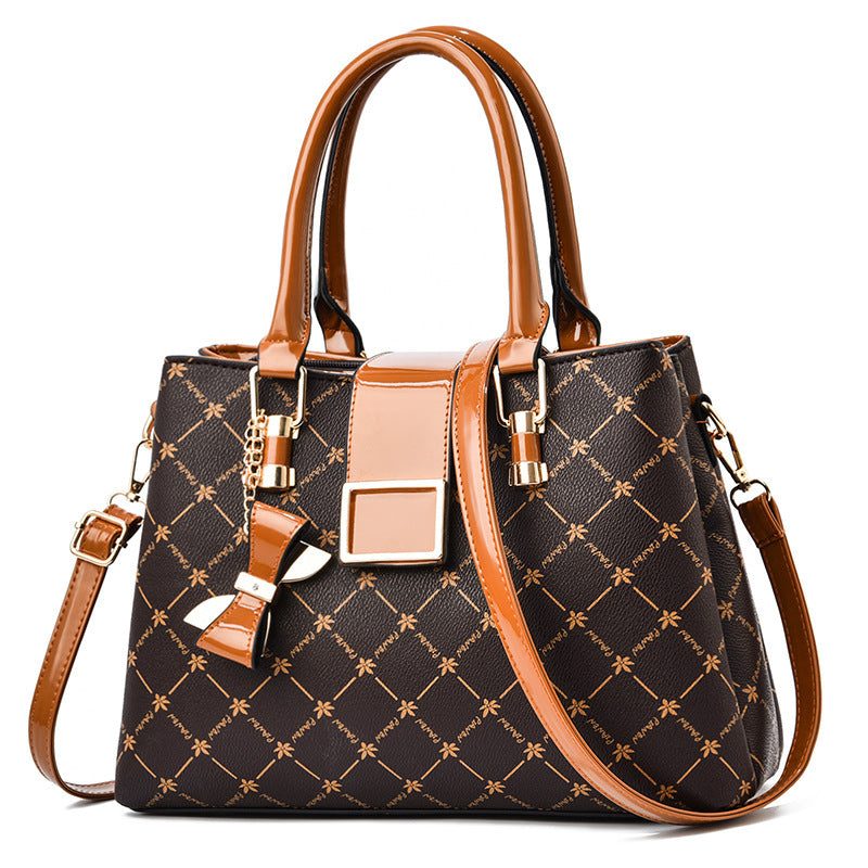 Brown and black patterned handbag with gold accents on a white background
